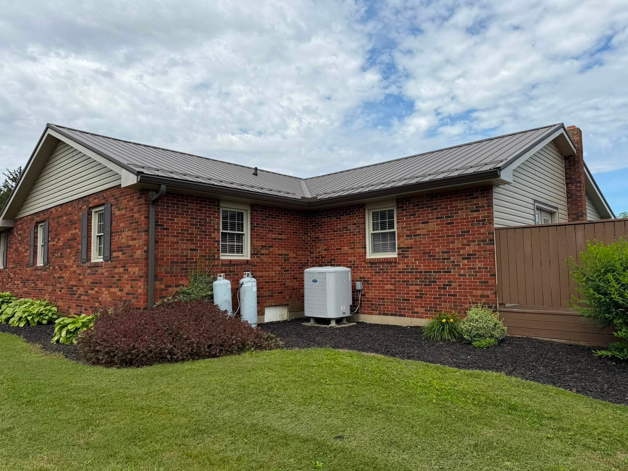 Rear view of brick home with finished roof