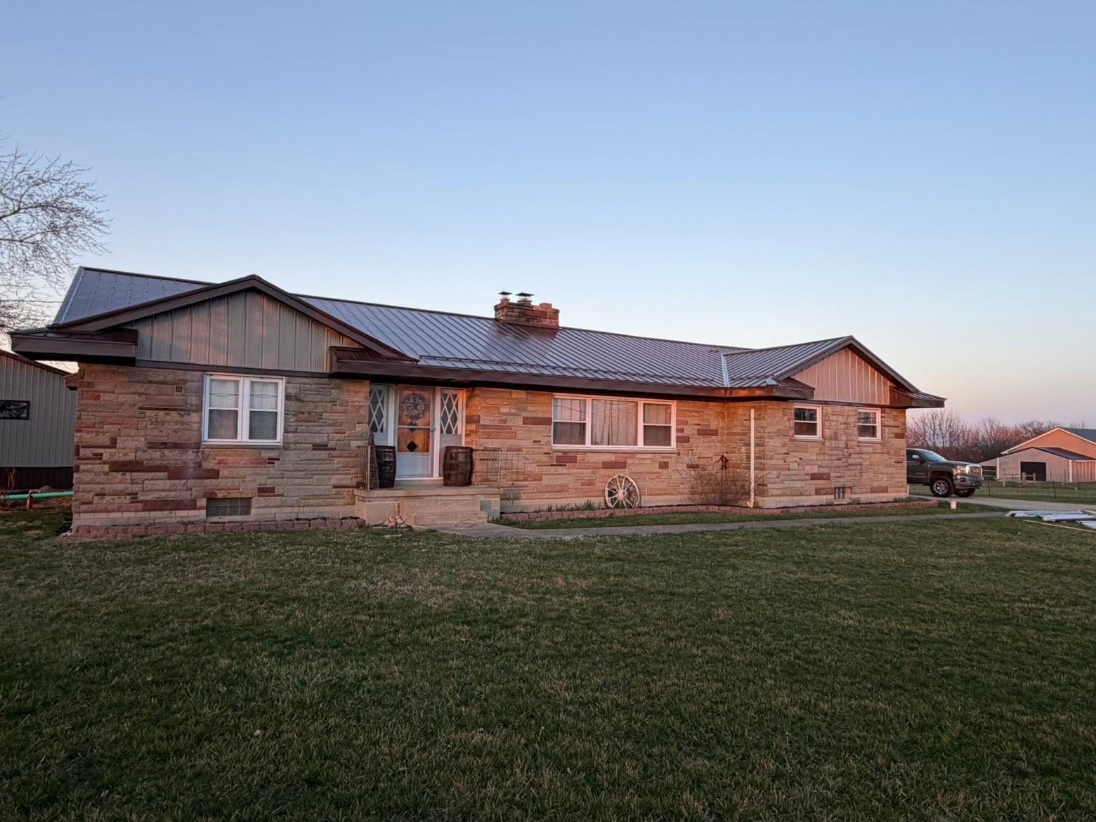 Wide brick ranch home with metal roof