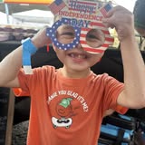 A child holding Shelby's themed glasses at an event
